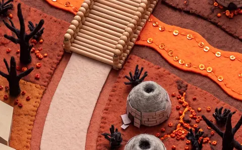 Ember: a kiln town of felt, orange ground and a bridge.